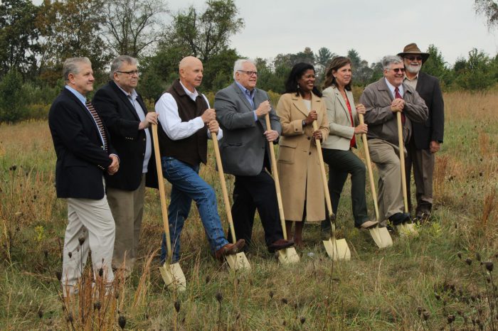 Group of people pressing shovels into the ground.